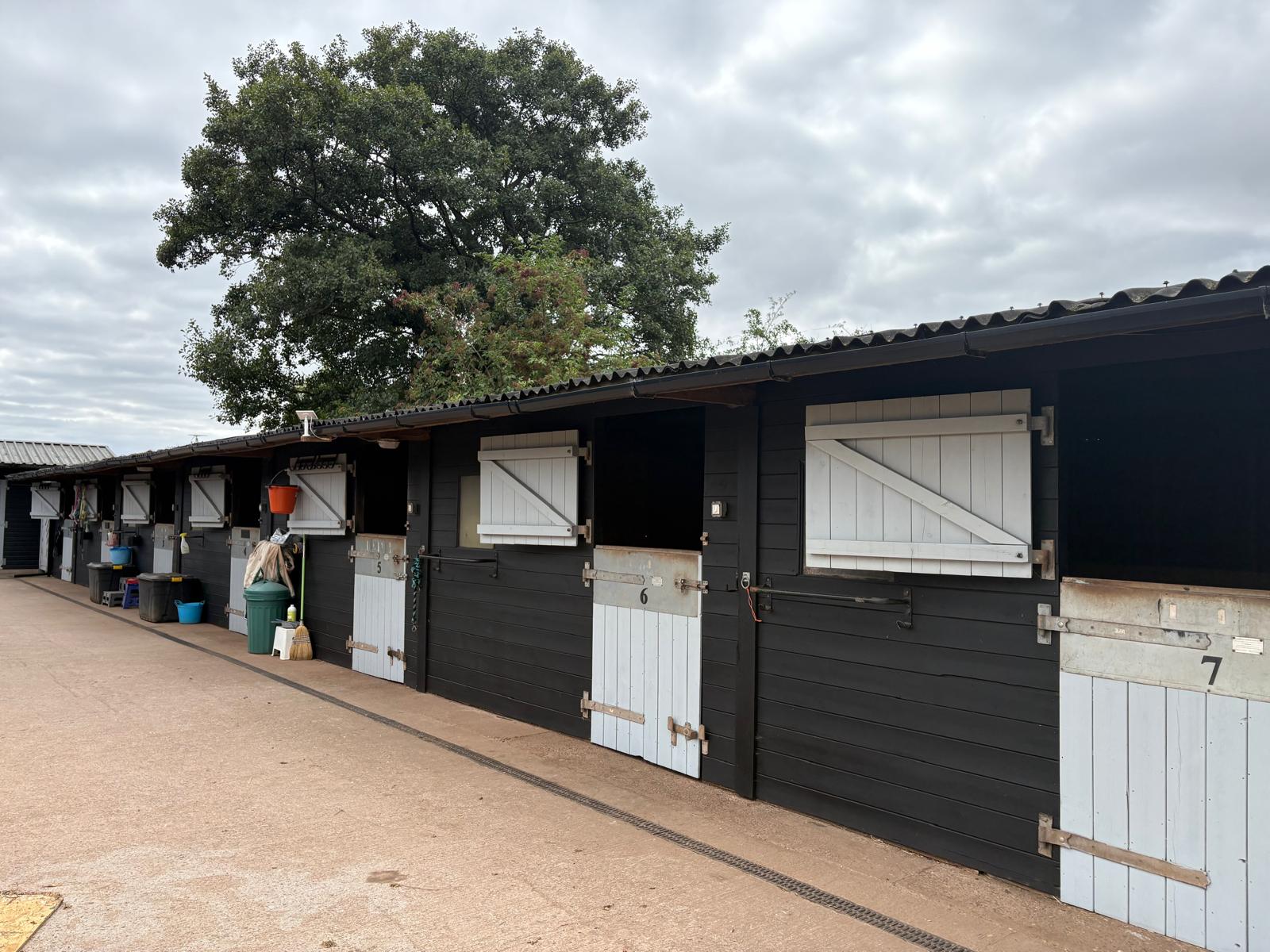 Black wooden stable block with white doors at Middleton Livery Yard